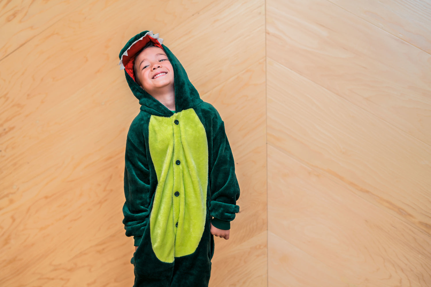 Little boy with a dark and light green dragon play costume on