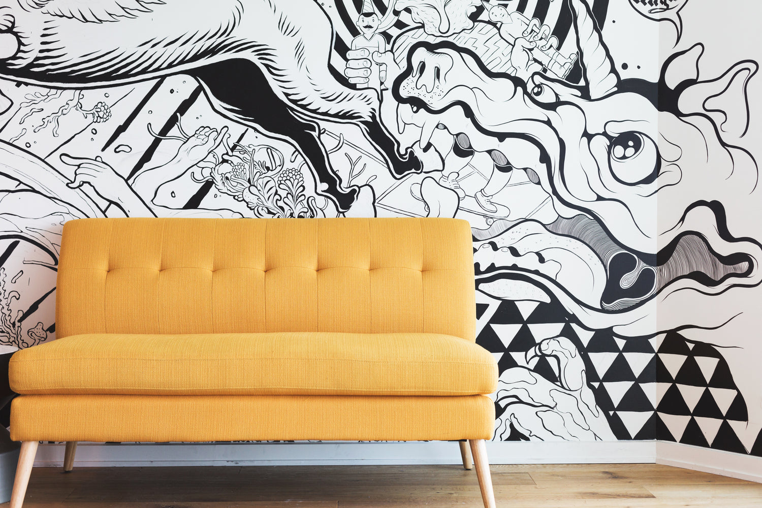 A yellow mid-century modern couch in front of a black and white mural