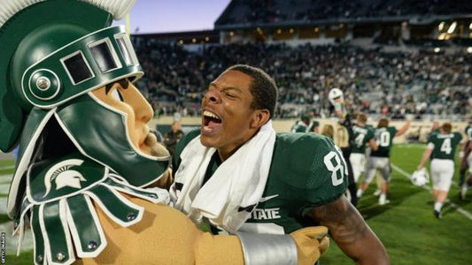 Michigan State Mascot, "Sparty" and player celebrating on field.